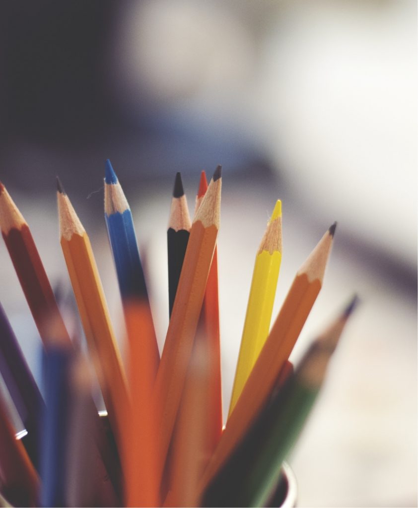collection of colored pencils sit in a cup on a desk at Montessori school